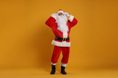Mutlu noeller. Noel Baba turuncu arka planda poz veriyor