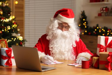 Noel Baba masadaki Noel mektuplarını imzalıyor.