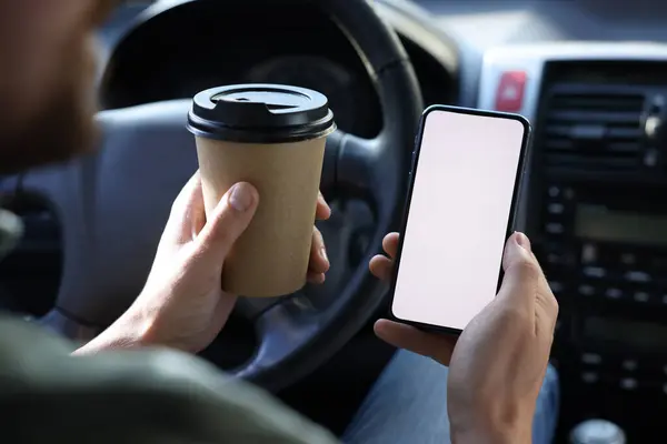 Coffee to go. Man with paper cup of drink and smartphone in car, closeup