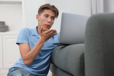 Bilgisayarla görüntülü konuşma yapan ve kanepede öpüşen mutlu genç adam. Uzun mesafeli ilişki