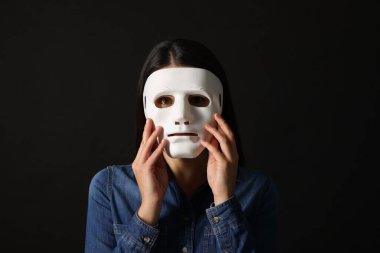 Çoklu kişilik konsepti. Siyah arka planda maskeli kadın