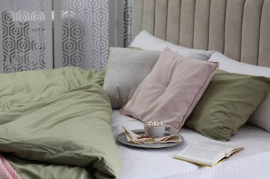 Modern oda içinde yeni şam fıstıklı çarşafları olan rahat bir yatak.