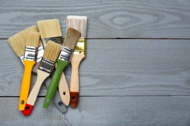 Gri ahşap masadaki farklı fırçalar, düz yatış. Metin için boşluk