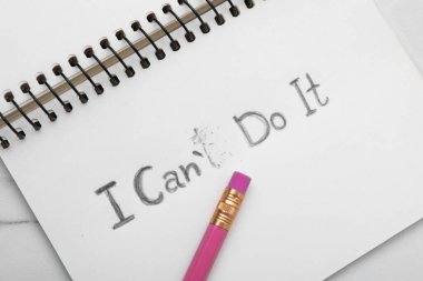 Motivasyon konsepti. Not defterinde I Can 't Do It' ten I Can 't Do It' e beyaz masadaki T harfini silmek, üst görünüm