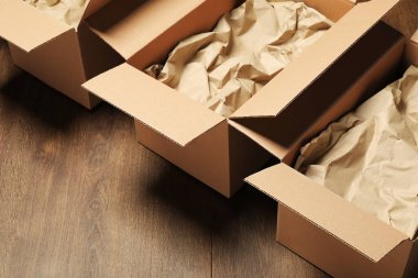 Ahşap zeminde buruşmuş kağıtlarla karton kutular aç. Paketleme malları