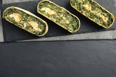 Somonlu lezzetli turta parçaları ve koyu dokulu masa üzerinde ıspanak. Metin için boşluk