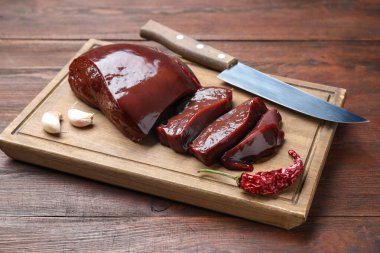 Biber, sarımsak ve bıçakla kesilmiş çiğ sığır ciğeri, ahşap masa, yakın plan