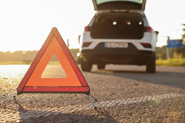 Warning triangle and broken car on roadside, selective focus