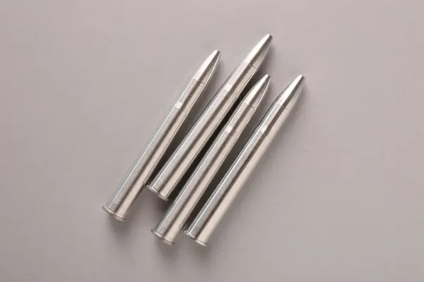 Many metal bullets on light grey background, flat lay
