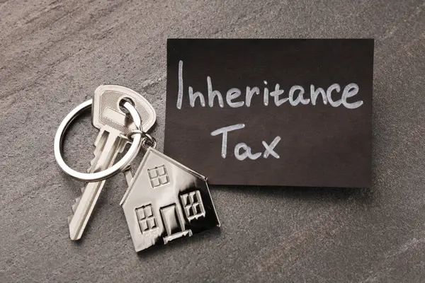 Inheritance Tax. Card and key with key chain in shape of house on grey table, top view