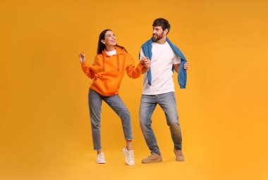 Mutlu çift turuncu arka planda dans ediyor.