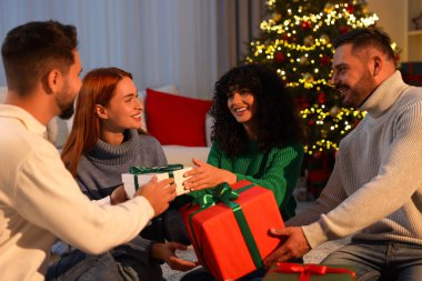 Noel kutlaması. Mutlu arkadaşlar evde hediyelerini değiş tokuş ederler