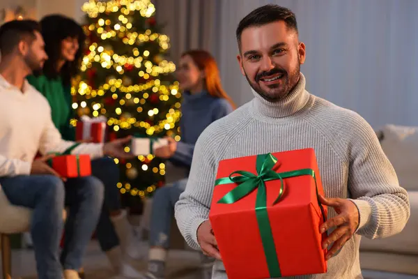 Arkadaşlar arasında Noel kutlaması. Evde hediye kutusu olan mutlu adam, seçici odaklı.