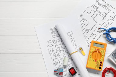 Beyaz ahşap masa üzerinde kablo diyagramları ve dijital çokölçer ile düz kompozisyon, metin için boşluk