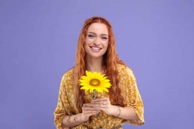 Mor arka planda ayçiçeği olan güzel genç hippi kadın.