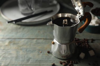 Moka demliğinde demlenmiş kahve, kırsal ahşap masada fasulye ve şeker küpleri, metin için yer