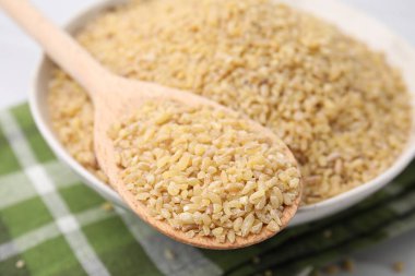 Tabakta çiğ bulgur olan kase ve kaşık, yakın plan.
