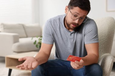 Evde koltukta akıllı telefondan konuşan kredi kartı olan duygusal bir adam. Dikkatli ol, sahtekar.