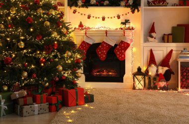 Oturma odasının içinde şömine ve şenlikli dekor var. Noel kutlaması