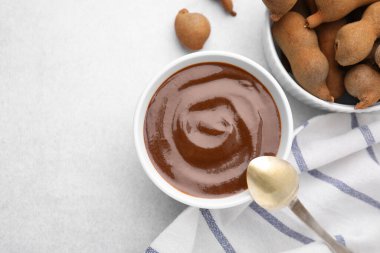 Bir kase demirhindi sosu, kaşık ve taze kapsüller ışık masasında, düz yerde. Metin için boşluk