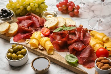 Şarküteri tahtası. Lezzetli Bresaola ve beyaz mermer masada diğer atıştırmalıklar.