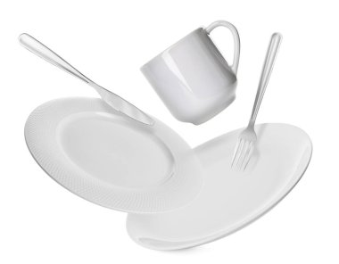 Temiz tabaklar, çatal, bıçak ve fincanın beyaz arka plana düşmesi