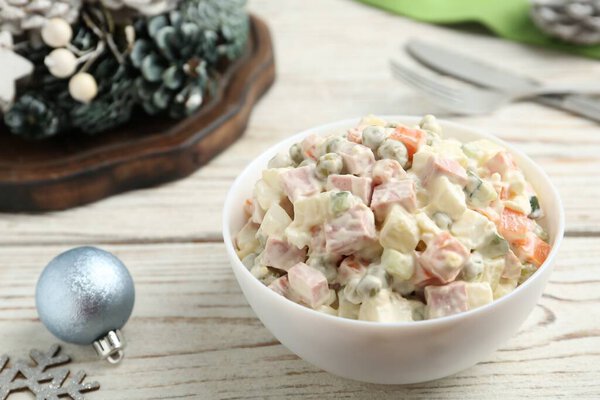 Традиционный русский салат Оливье подается на белом деревянном столе