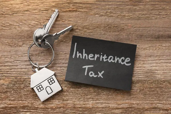 Inheritance Tax. Card and keys with key chain in shape of house on wooden table, top view
