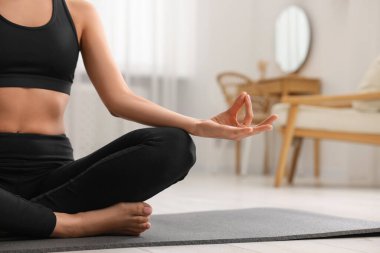 Evde yoga minderinde Padmasana egzersizi yapan bir kadın, yakın çekim ve mesaj için yer. Lotus pozu