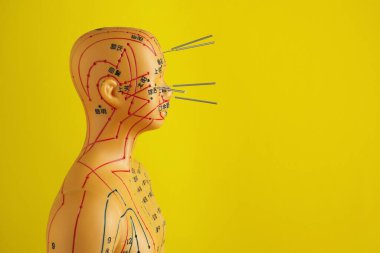 Akupunktur - alternatif tıp. Sarı arkaplan üzerinde iğneler olan insan modeli, metin için boşluk