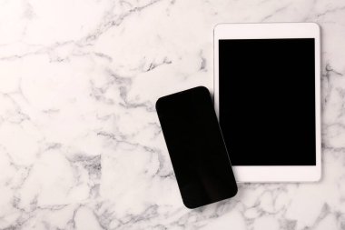Tablet ve akıllı telefon beyaz mermer masa üzerinde boş ekranlar, düz yatıyordu. Metin için boşluk