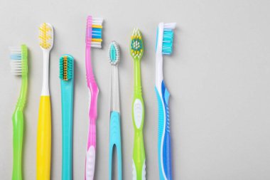 Arka planda birçok farklı diş fırçası, düz bir zemin. Metin için boşluk