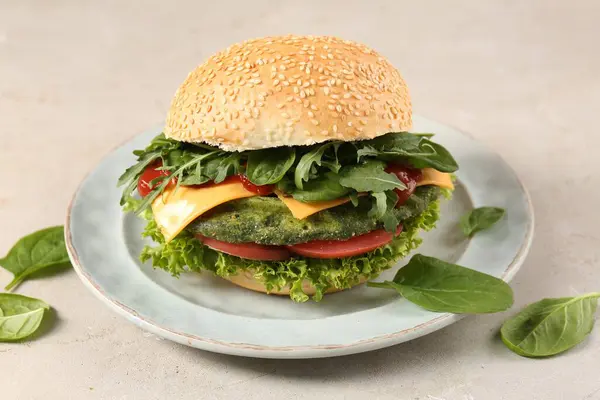 Tasty vegetarian burger with spinach cutlet, cheese and vegetables on white table, closeup