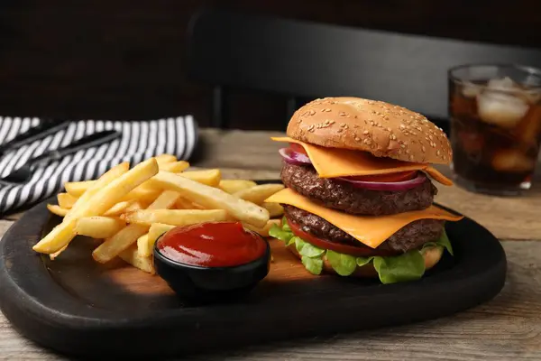 Delicious burger with meat cutlets, french fries and sauce on wooden table, closeup