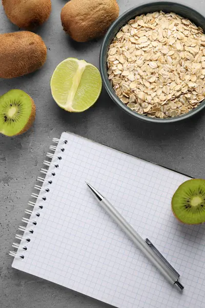 Healthy diet. Notebook, pen and products on grey table, flat lay