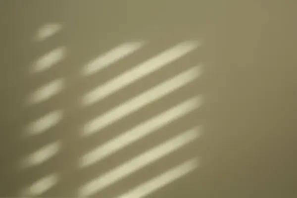 Light and shadow from window on beige wall indoors