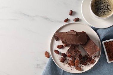 Lezzetli sütlü çikolatalar, kakao çekirdekleri ve beyaz mermer masada kahve, düz yatak. Metin için boşluk