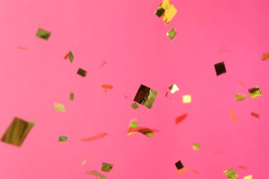 Pembe arka planda parlayan altın konfeti