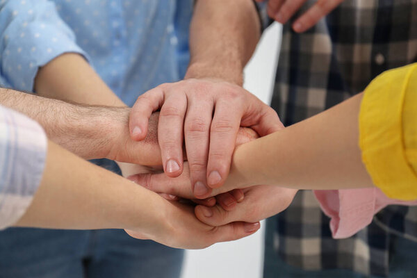 People holding hands together in office, closeup