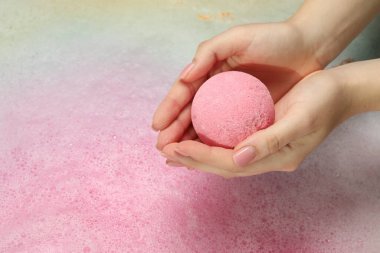 Suyun üzerinde köpükle banyo bombası tutan kadın, yakın plan. Metin için boşluk