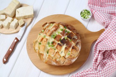 Taze pişmiş ekmek tofu peyniri, yeşil soğan ve beyaz ahşap masa üzerinde bıçak, düz yatıyordu.