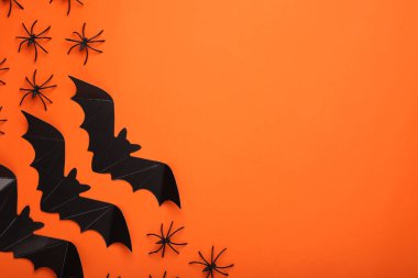 Turuncu arka planda kağıt yarasalar ve örümceklerle düz kompozisyon, metin için boşluk. Cadılar Bayramı