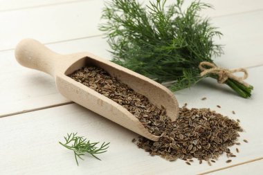 Kuru tohumlar ve taze dereotu beyaz ahşap masada, yakın plan.