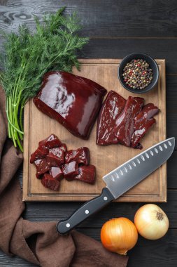 Çiğ sığır ciğerini soğanla, dereotuyla ve baharatlarla ahşap masada kes.