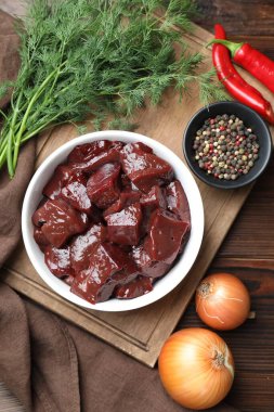 Çiğ sığır ciğerini soğan, baharat, kırmızı biber ve ahşap masada dereotla kes.