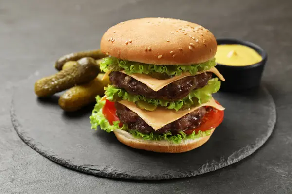 Smaczny Hamburger Pasztecikami Ogórkami Sosem Czarnym Stole — Zdjęcie stockowe