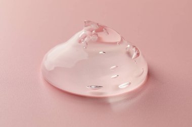 Pembe arka planda temiz kozmetik jel örneği, yakın plan.