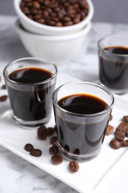 Bir bardak kahve likörü ve beyaz mermer masada fasulye, yakın plan.