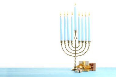 Hanuka kutlaması. Menorah, dreidels ve hediye kutuları açık mavi ahşap masa beyaz arka plan karşı