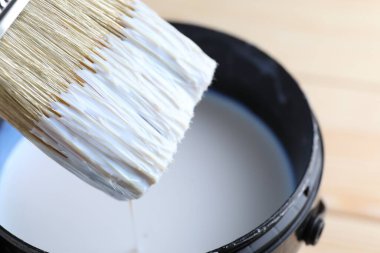 Fırçayı teneke kutuya daldırıyorum. Masada cila var, yakın plan.